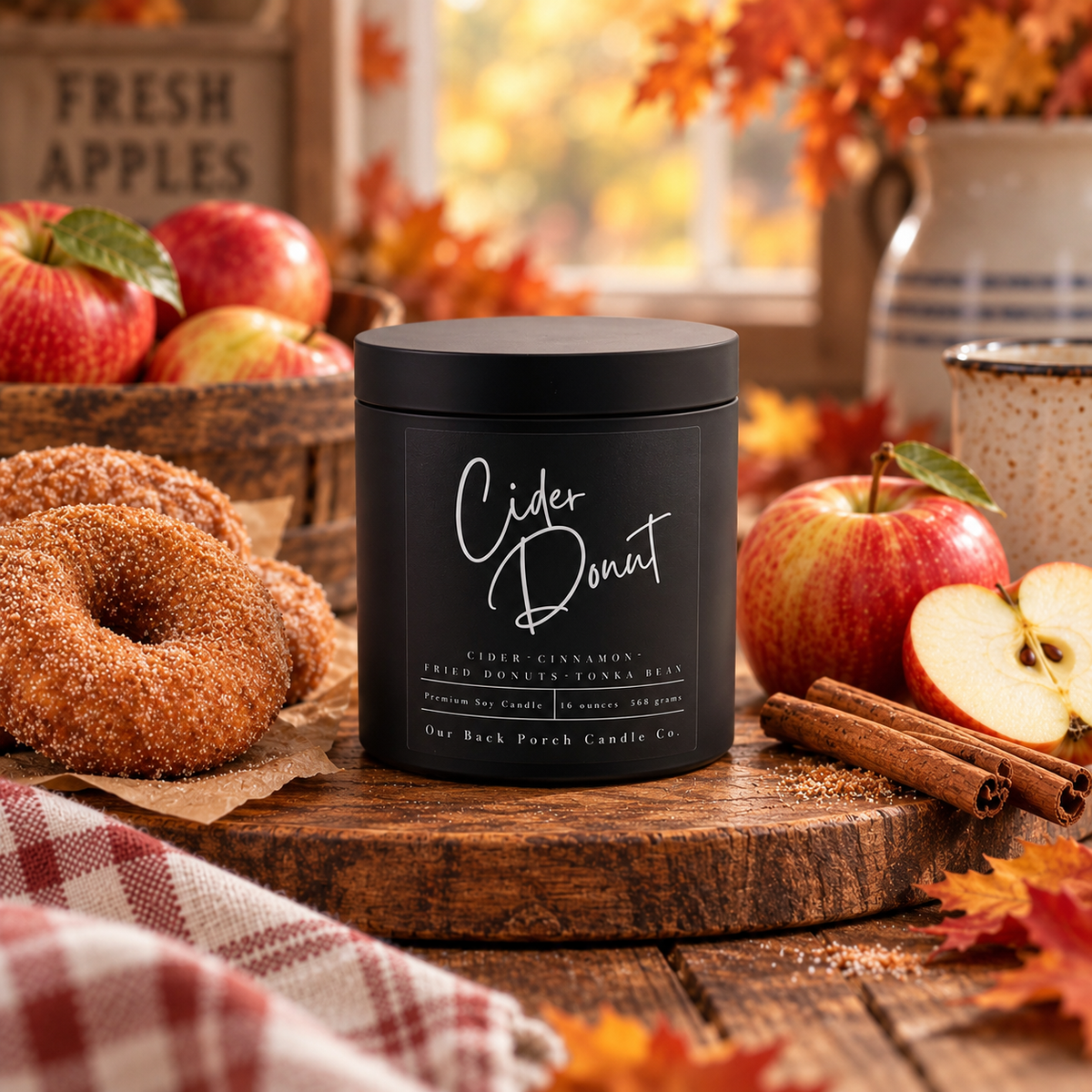 Cider Donut matte black 16oz soy candle by Back Porch Candle Co., the Black Tin option for Apple Cider Donuts, styled with apple cider donuts, fresh apples and cinnamon in an autumn kitchen setting.