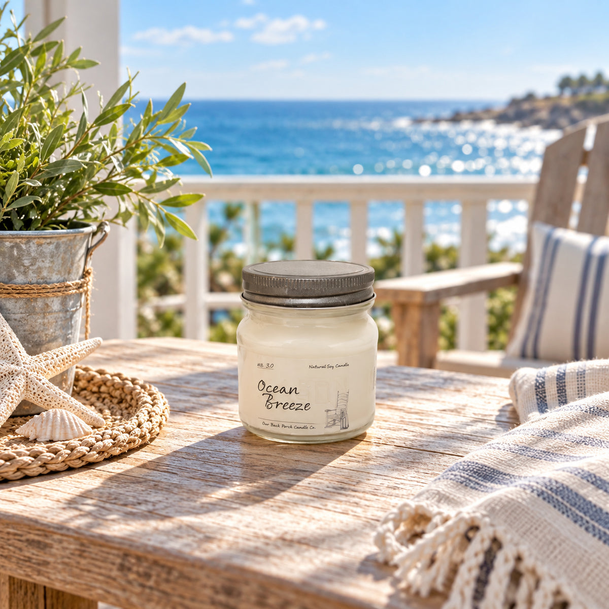 Ocean Breeze 8 oz soy candle by Back Porch Candle Co. styled on a sunny coastal porch with ocean views and soft blue accents.