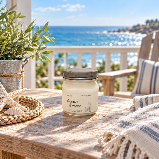 Ocean Breeze 8 oz soy candle by Back Porch Candle Co. styled on a sunny coastal porch with ocean views and soft blue accents.